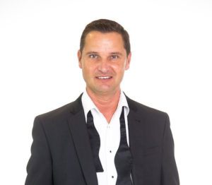 Andy Mack swing singer wearing open black bowtie with hands in his pockets looking cool