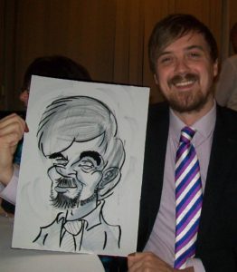 Caricature Drawn by David and Held up by a Smiling Happy Party Guest