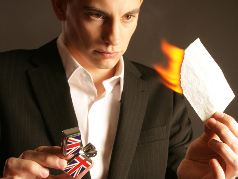 Close up magician Matt burning a piece of paper as part of a magic trick