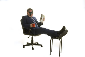 Blindfolded comedy mind reader David relaxes with his feet up mug of tea in hand reading a newspaper using his secret powers