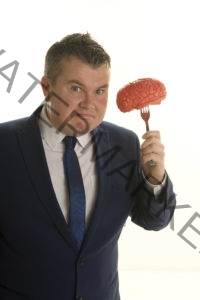 Mind Reader David Formally Dressed in a Dark Blue Suit Holding a Human Brain on a Fork With a Mischievous Grin on His Face