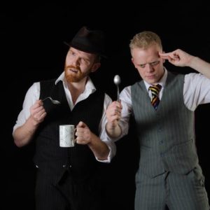 Stage Magicians Griffin & Jones Perform A Mind Boggling Tea Spoon Bending Comedy Routine Against A Black Background