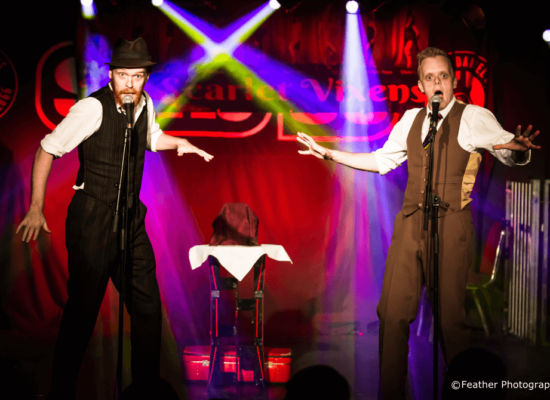 Comedy Magicians Griffin & Jones Performing Live Against A Colourful Stage Background