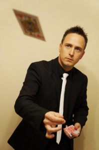 Close up magician Kevin flicks a playing card through the air as part of one of his spectacular close up magic tricks