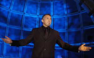 TV Celebrity Marc Paul Standing Against A Blue Background With His Arms Outstretched Is One Of The World's Top Mind Readers