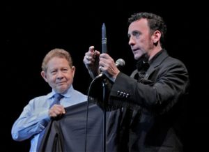 Corporate magician Paul Zenon cuts and restores the jacket of an audience member using a sharp dagger