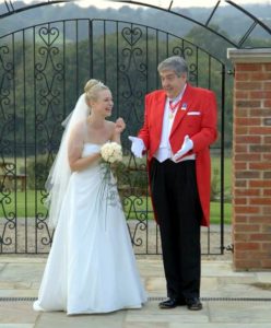 Red Coat Toastmaster Nigel laughing with Bride outside of the wedding venue