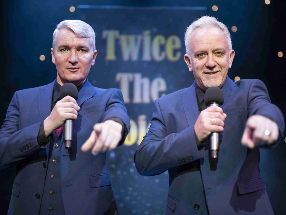 Twice The Voice Retro Party Duo Pointing To Audience In Front Of A Twice The Voice Backdrop