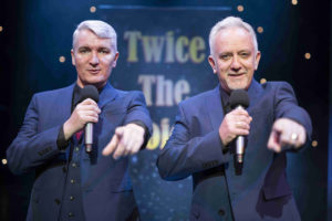 Twice The Voice Retro Party Duo Pointing To Audience In Front Of A Twice The Voice Backdrop