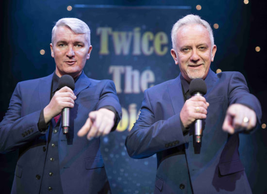 Twice The Voice Retro Party Duo Pointing To Audience In Front Of A Twice The Voice Backdrop