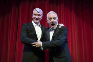Twice The Voice Sharing A Joke In Front Of Red Theatre Tabs