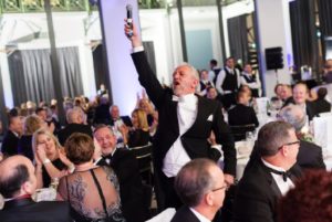 Singing Master Of Ceremonies At Corporate Event Holding Microphone Aloft