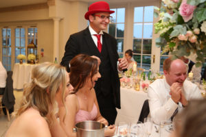 Danny Close Up Magician Performing At A Wedding Wearing A Red Bowler Hat