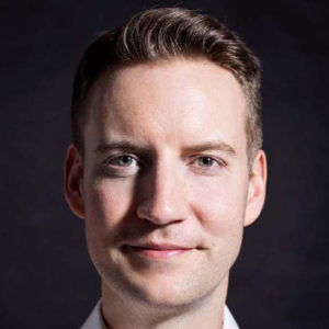 Christopher Close Up Magician Head Shot Against A Black Background