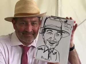 Steve Caricaturist Man With Hat Displaying His Caricature