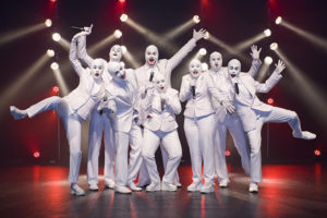 Voca People Take To The Stage Against A Red Background