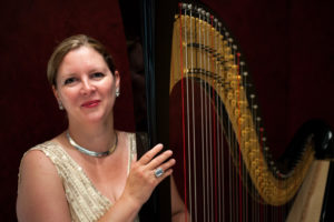 Fiona Harpist In White Gown Against A Black Background