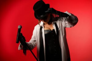 Shania Twain Tribute Act Represented By First & Foremost Entertainment Strikes A Pose Against A Muted Red Background