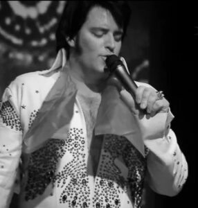 A black and white publicity photograph of Elvis Presley tribute act