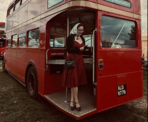 Mitzi Metford vintage singer standing on the platform of a vintage red double decker bus