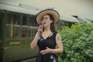 Vintage singer Mitzi Metford performing on the platform of a steam railway in Brighton East Sussex